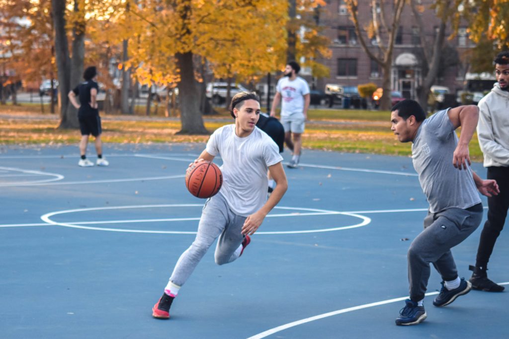man in white nike crew neck t-shirt and gray pants playing basketball during daytime